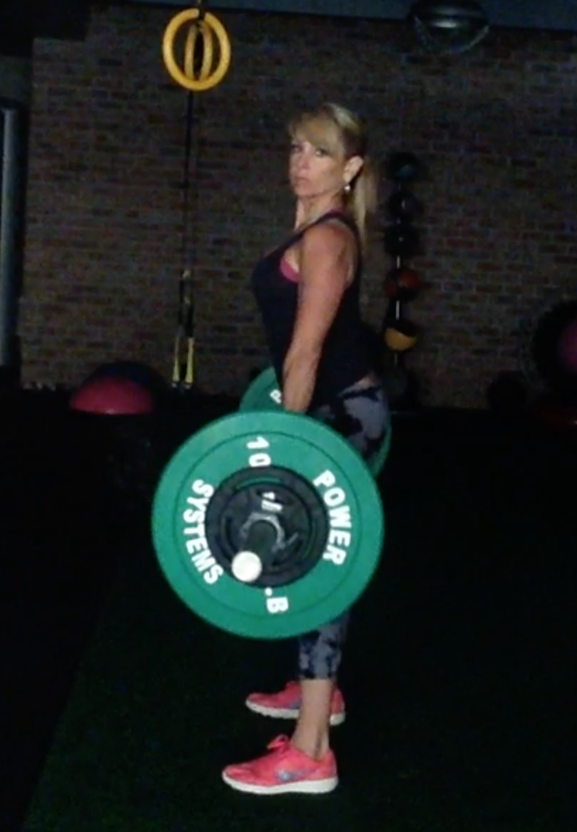 Chalene Johnson holding a green disc in a gym
