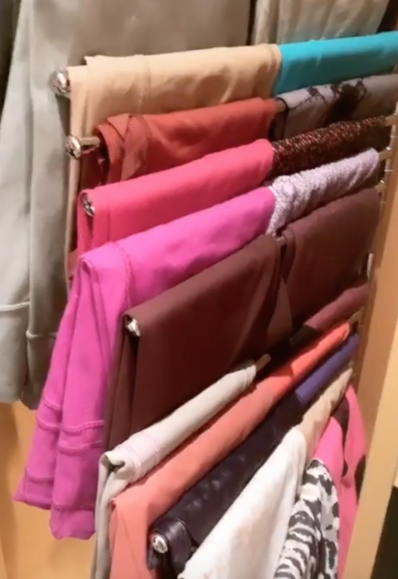a rack of folded clothes in a closet